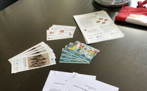 Ein Tisch mit Papierstapeln und einem roten Stoffbeutel, bereit für ein Meeting oder Seminar.