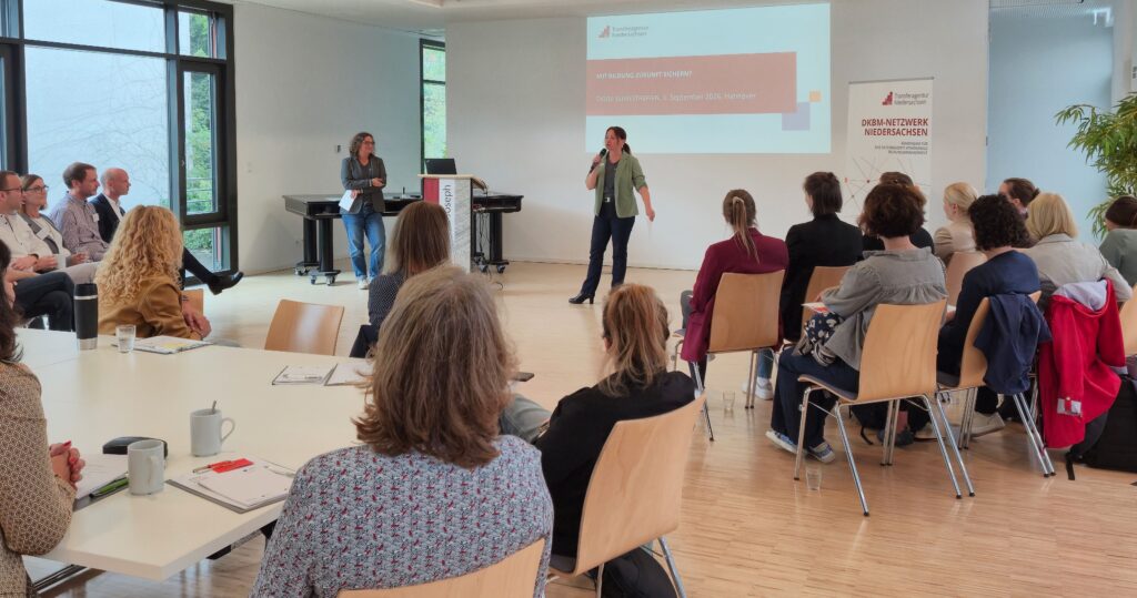 Ein Seminar mit Präsentation, bei dem eine Person spricht und Zuhörer aufmerksam folgen.